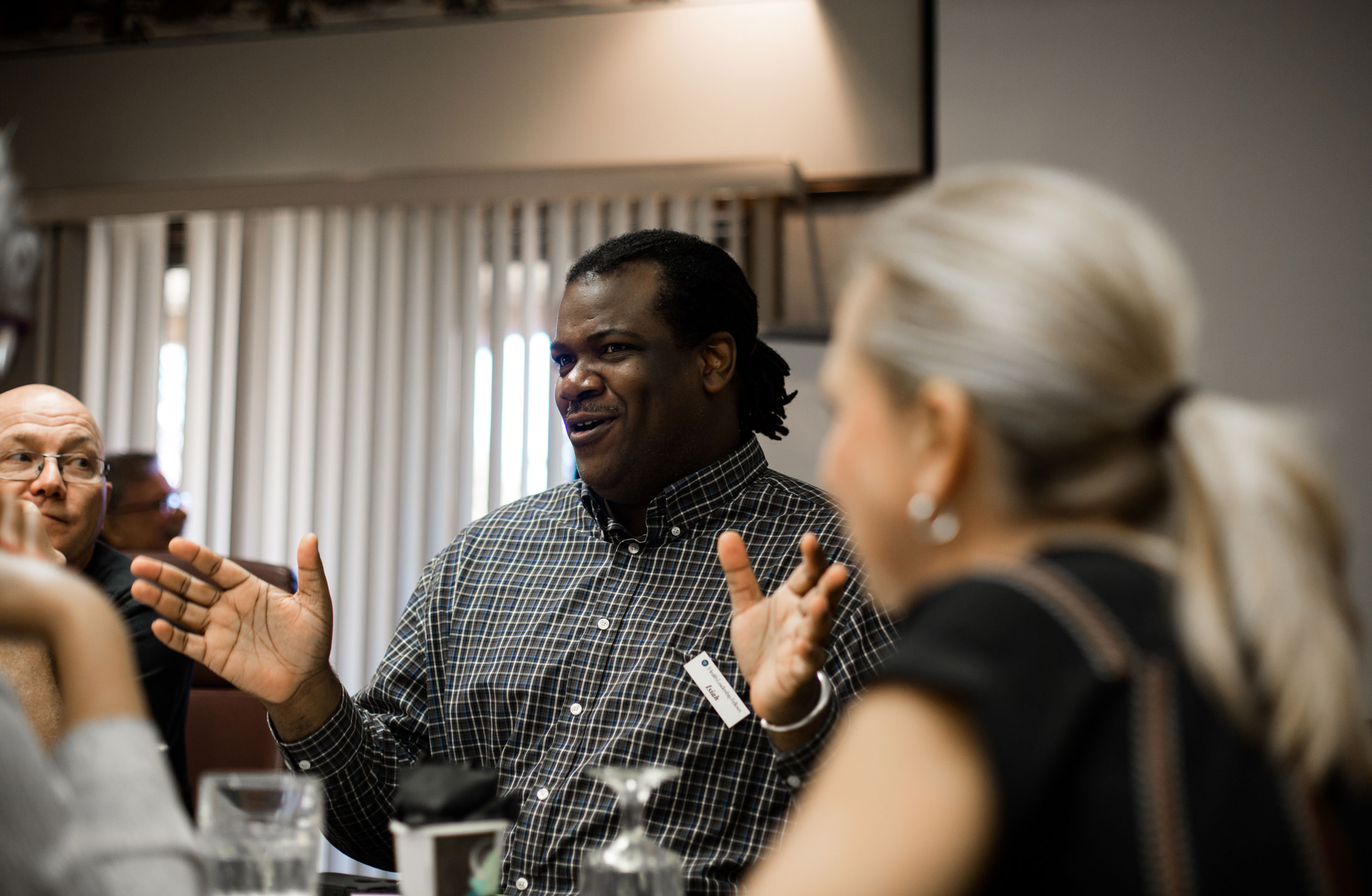 Man at event speaking to group of adults at a table