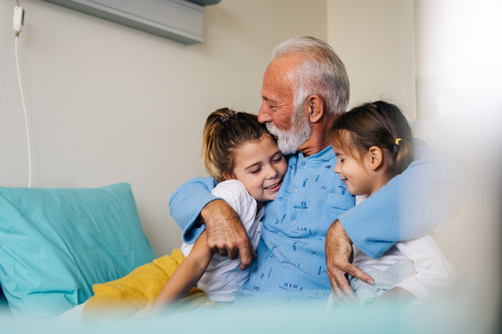 Grandfather hugging two granddaughters, one under each arm