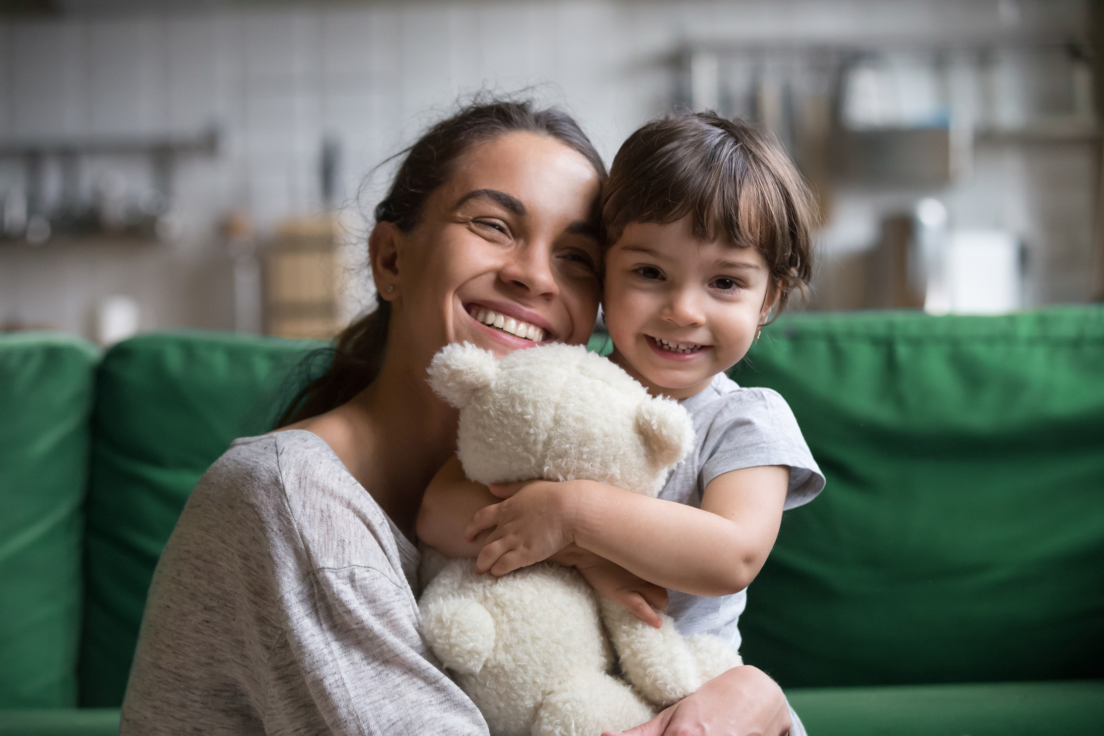 Young adult woman holding little girl with teddy bear